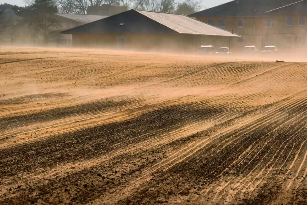 Dusty farmland with farm buildings at sunset