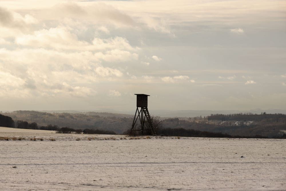 An elevated hunting tower against a cloudy sky